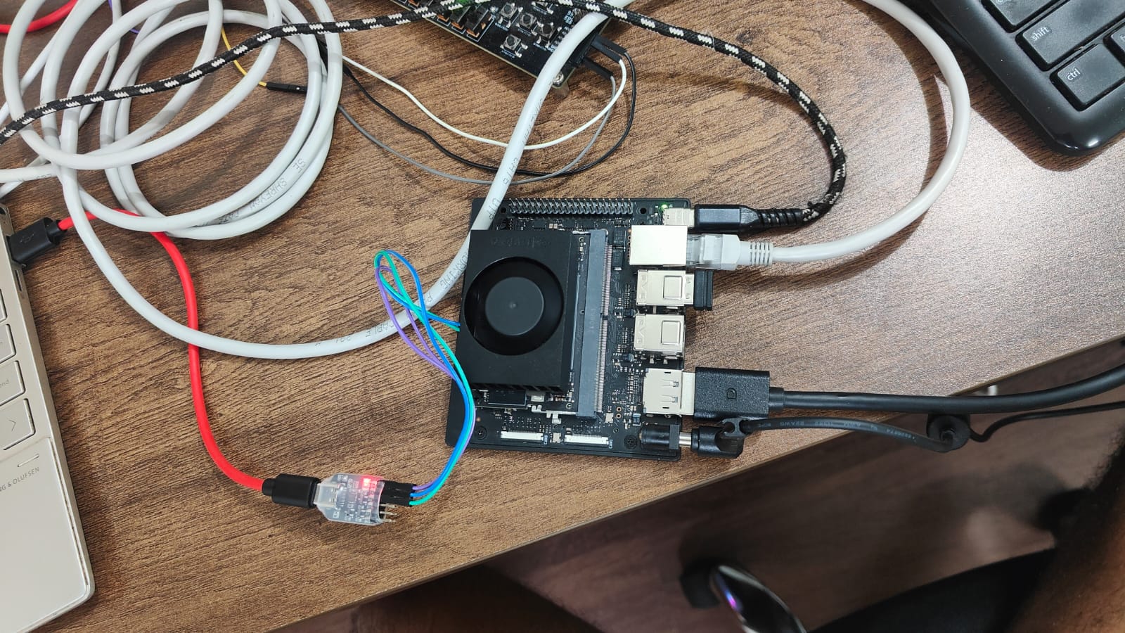 The NVIDIA Jetson Orin Nano developer kit on the desk, connected by a direct Ethernet cable to the laptop, a serial console adapter, and a DisplayPort cable to a monitor.